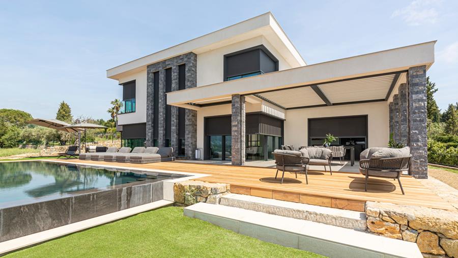 Des stores et une toiture en lames abritent une villa baignée de soleil